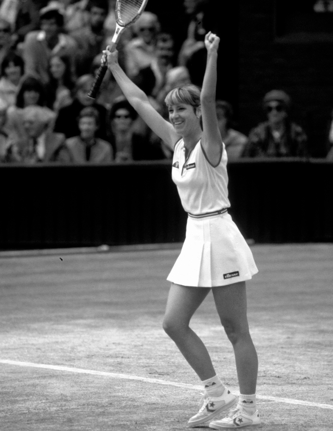 Chris Evert celebrating on a court with a racket raised, surrounded by spectators.